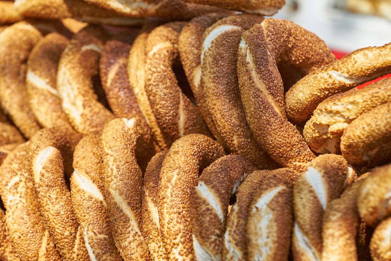 A detailed close-up of freshly baked, sesame seed-covered bread rings, showcasing texture and color.