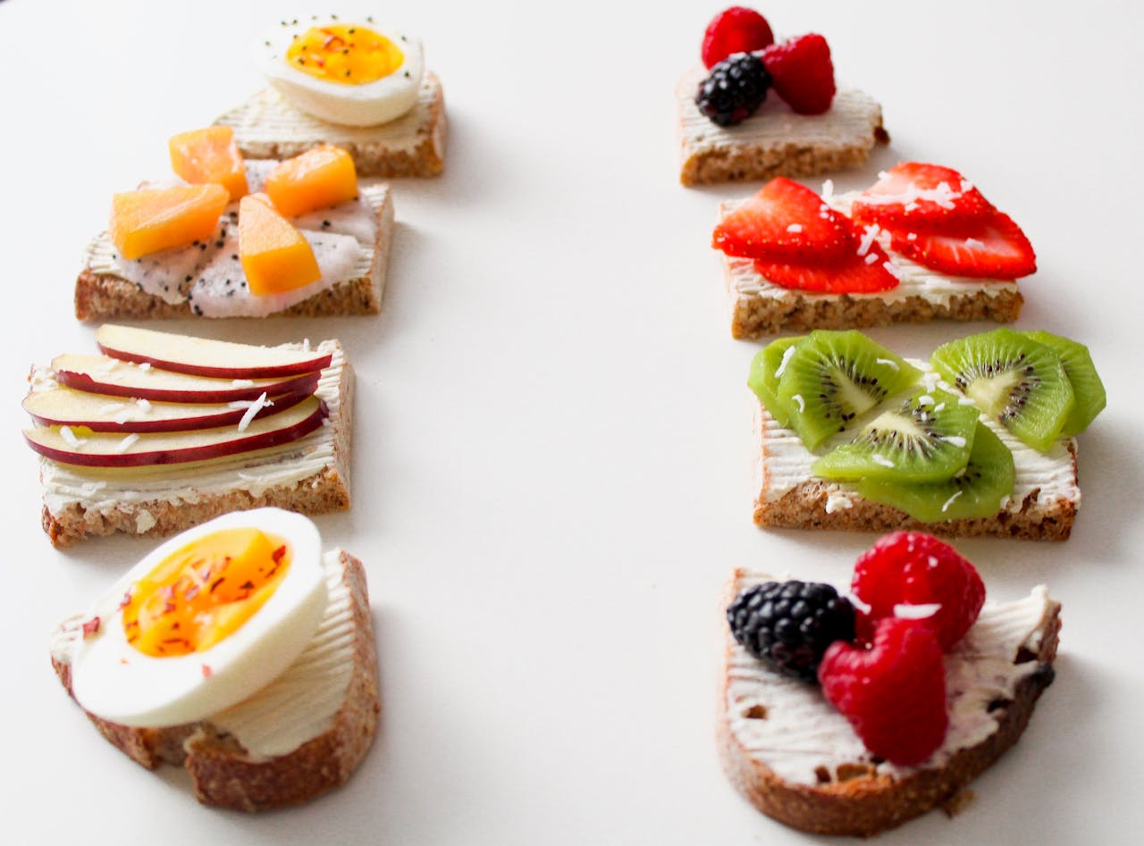 Delicious selection of open-faced fruit and egg sandwiches on whole grain bread for a healthy breakfast.